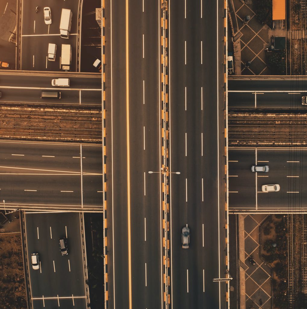 Sun at top down traffic cross road aerial. Urban transportation with cars, trucks, buses at sunlight